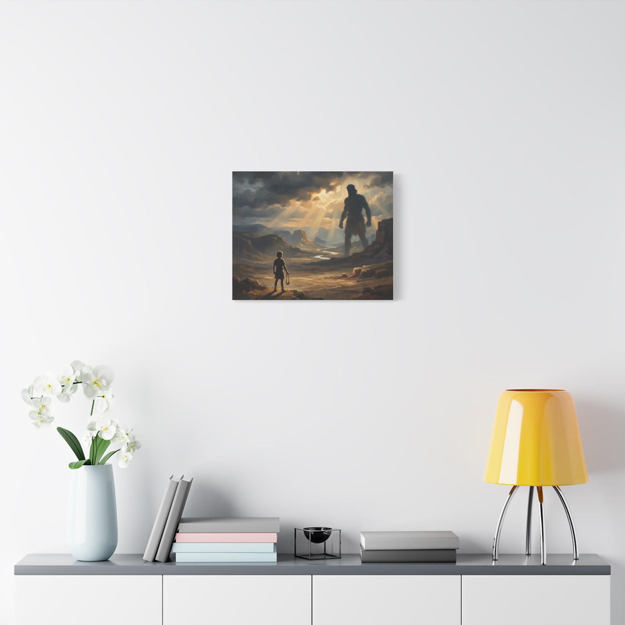 An oil painting style print on a stretched canvas depicting a young boy holding a sling, looking out across a sunlit desert valley toward the giant shadow silhouette of Goliath in the distance. -3